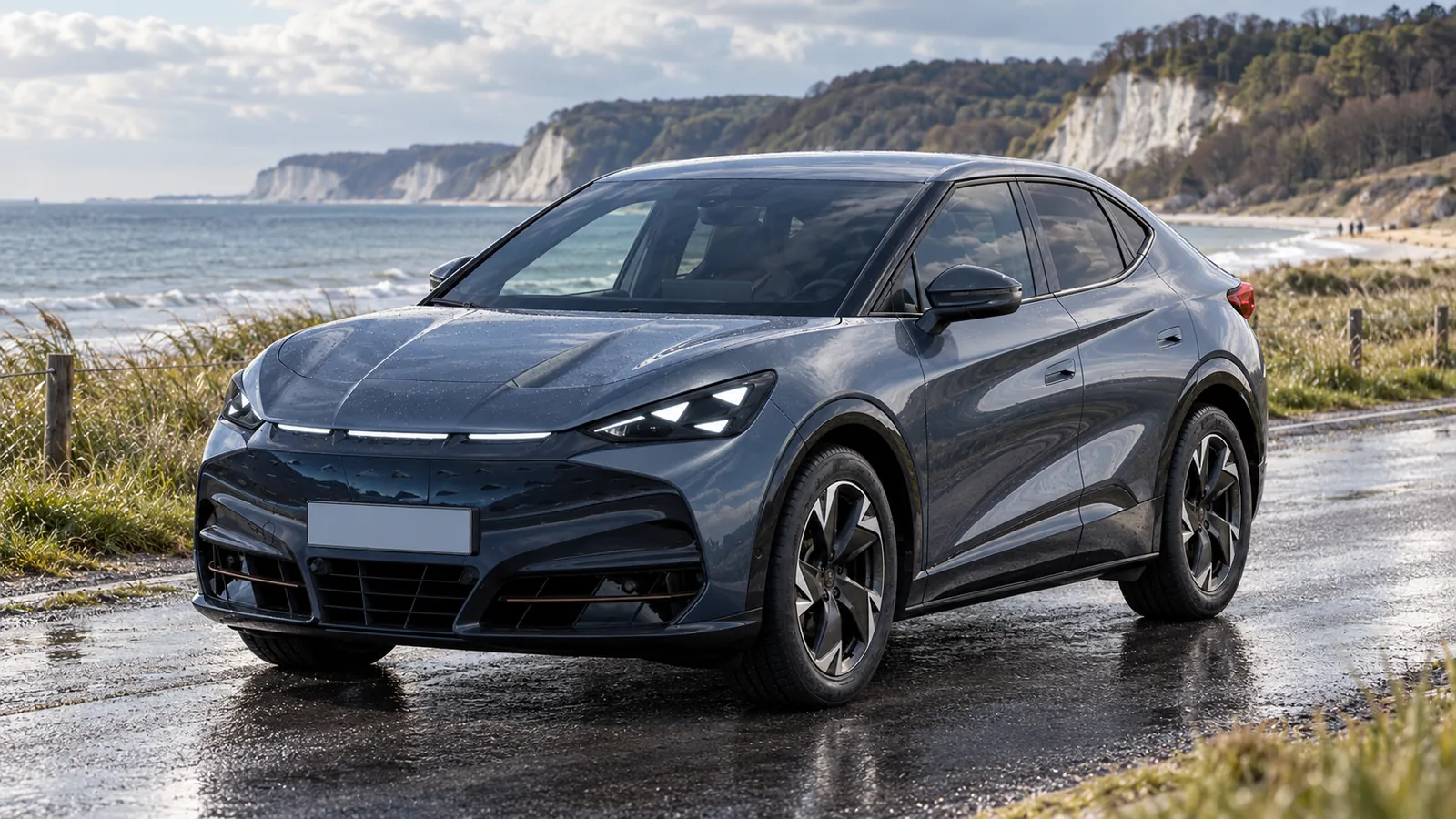 Grauer CUPRA Tavascan an einer Küstenstraße.